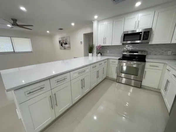 a kitchen with granite countertop white cabinets and stainless steel appliances