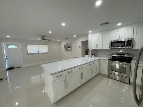 a kitchen with granite countertop a sink and white cabinets