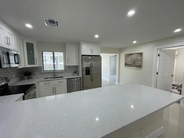 a large kitchen with kitchen island a sink stainless steel appliances and cabinets