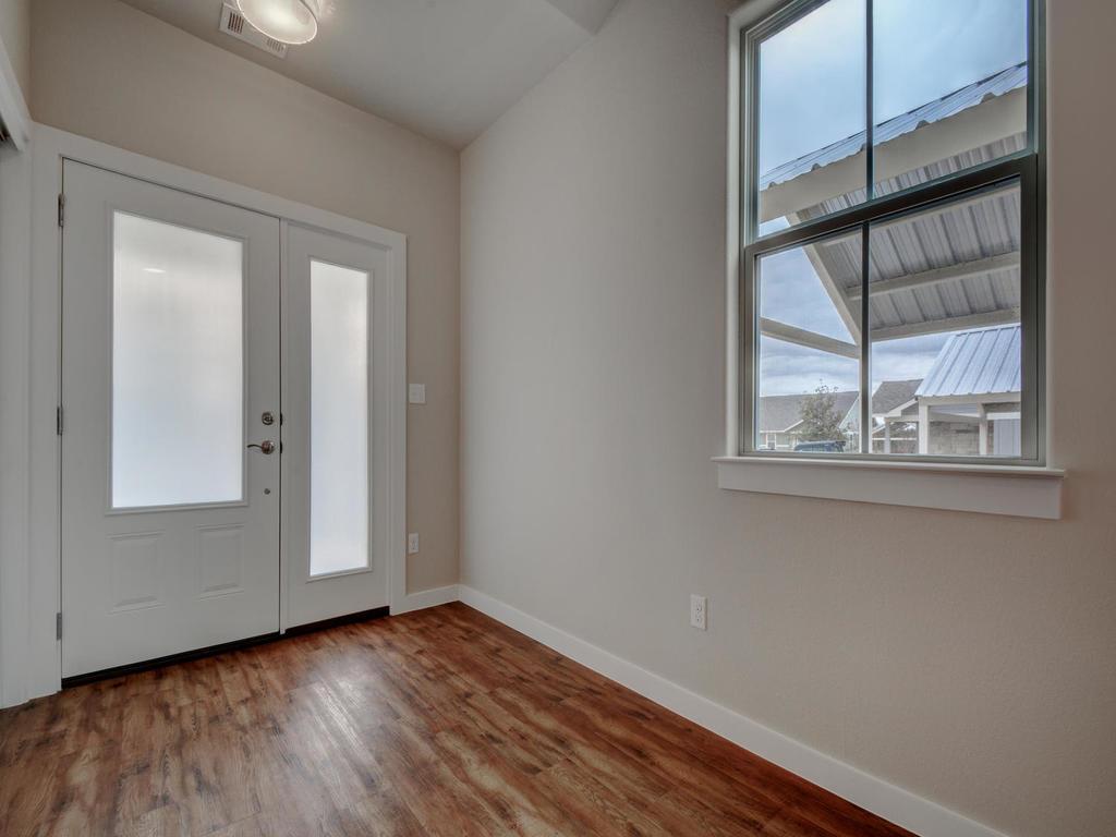 240 Rose Drive, Unit A Dripping Springs, TX 78620 - Photo 7 of 30 an empty room with wooden floor and windows