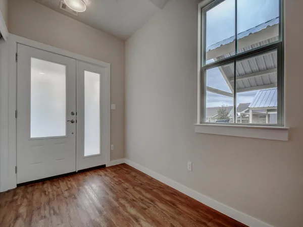 an empty room with wooden floor and windows