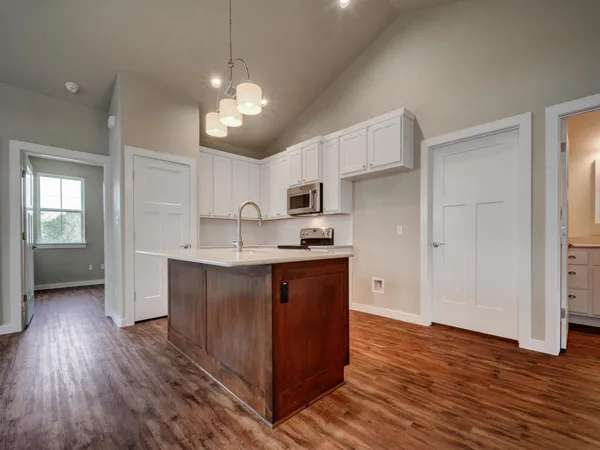 an empty room with wooden floor chandelier and windows