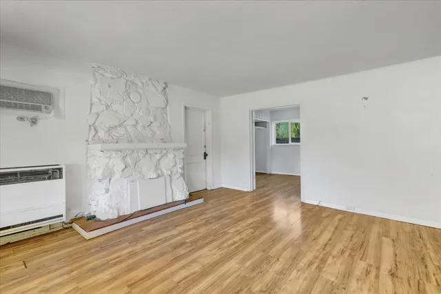 a view of an empty room with a window and wooden floor