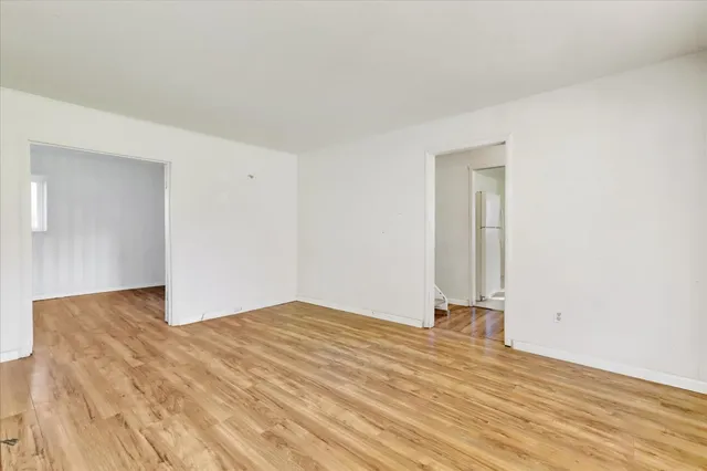 a view of a hallway with wooden floor a bathroom and a sink