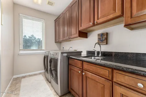a kitchen with stainless steel appliances granite countertop a sink a washer and dryer with wooden cabinets