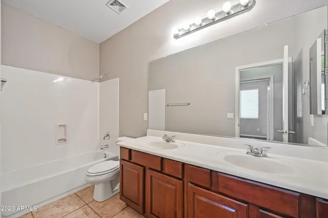 a bathroom with a double vanity sink a toilet and shower