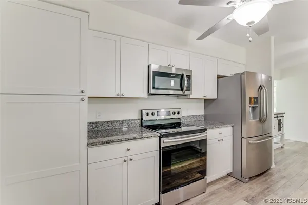 a kitchen with stainless steel appliances white cabinets white stove a microwave and a refrigerator