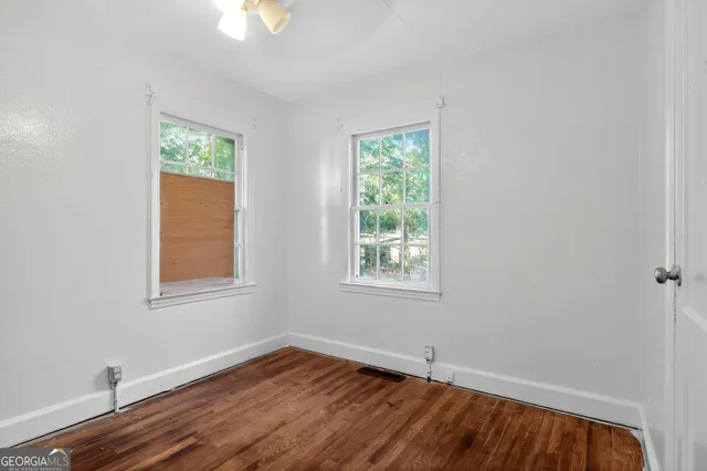 an empty room with wooden floor and windows