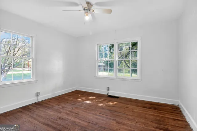a view of an empty room with wooden floor and a window