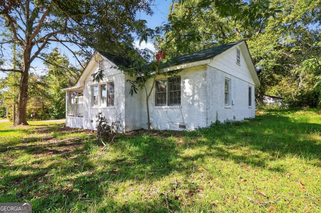 a backyard of a house with plants and large tree