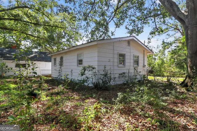 a backyard of a house with plants and large trees
