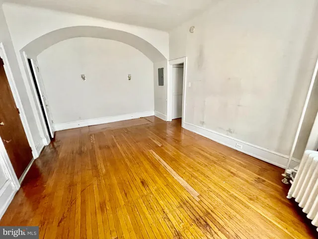 a view of an empty room with wooden floor and a bathroom
