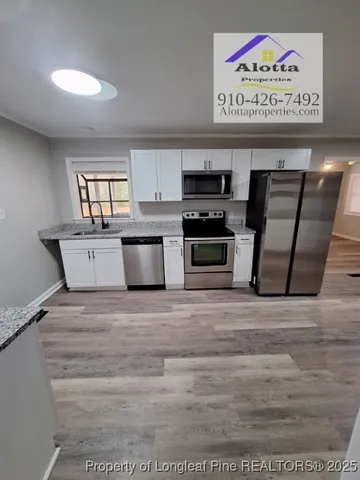 a view of kitchen with stainless steel appliances wooden floor and window