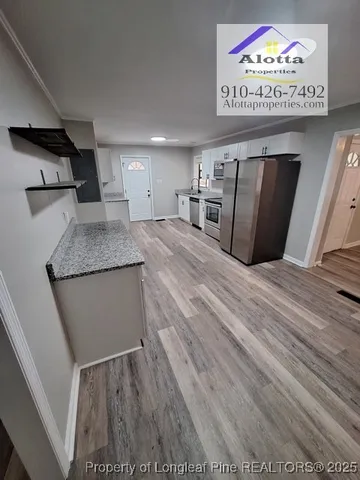 a view of a refrigerator in kitchen and an empty room