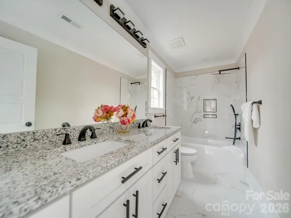 a bathroom with a granite countertop sink mirror and a bath tub