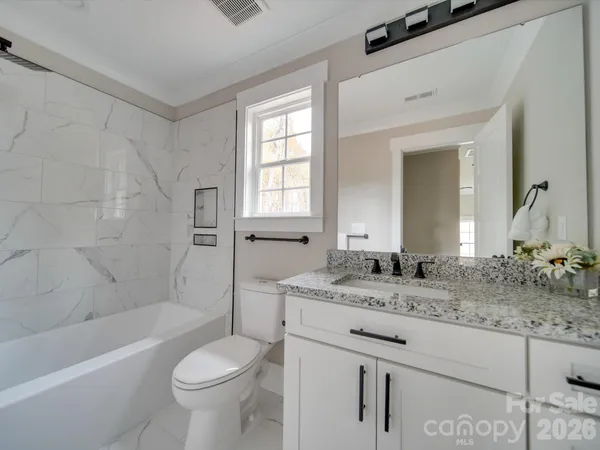 a bathroom with a granite countertop sink toilet mirror and bathtub