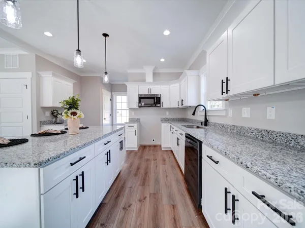 a large kitchen with granite countertop lots of counter space and wooden floor