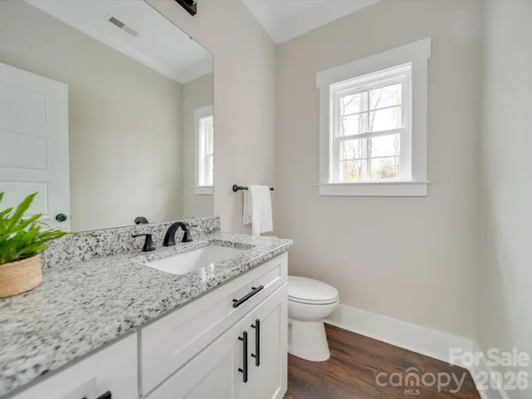 a bathroom with a granite countertop toilet a sink and a mirror