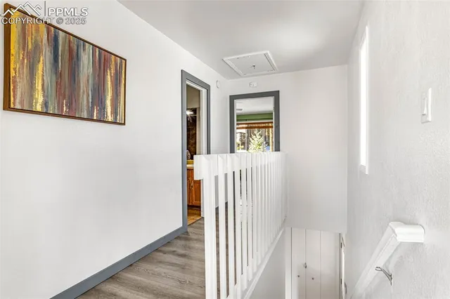 a view of a hallway with wooden floor and a bathroom