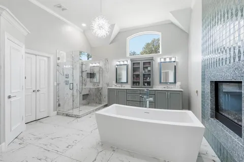 a spacious bathroom with a tub a double vanity sink a mirror and shower