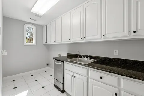 a kitchen with white cabinets and sink