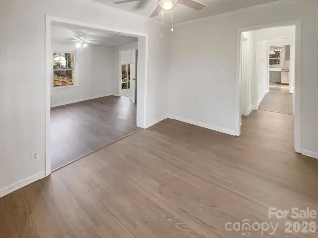 a view of an empty room with a window and wooden floor