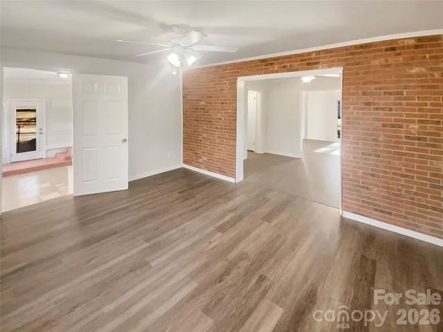 an empty room with wooden floor closet and windows