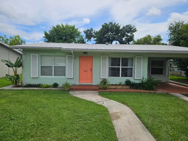 a front view of a house with a yard and potted plants