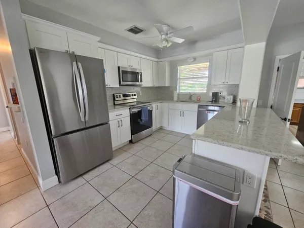a kitchen with stainless steel appliances granite countertop a refrigerator stove a sink dishwasher and microwave