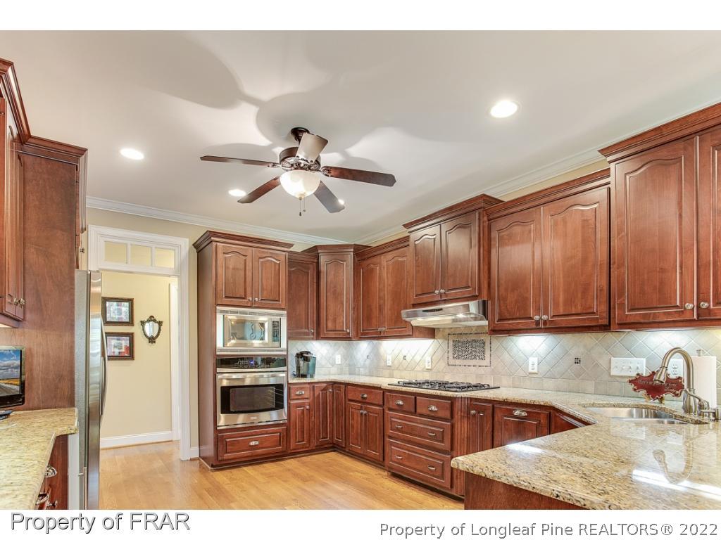 1517 Epic Way Hope Mills, NC 28348 - Photo 12 of 36 a kitchen with stainless steel appliances granite countertop a refrigerator a sink dishwasher a stove with wooden cabinets and floor