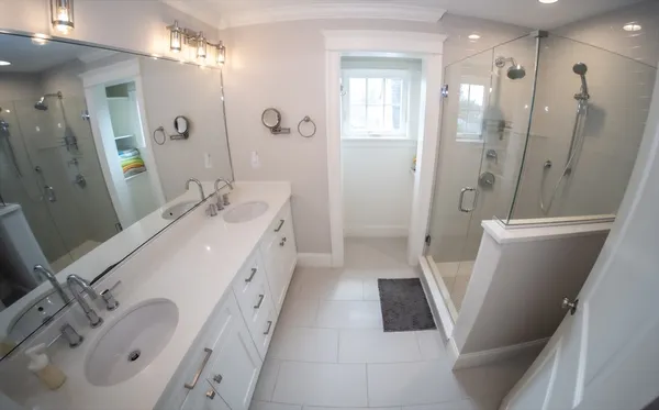 a spacious bathroom with a double vanity sink a mirror and a shower