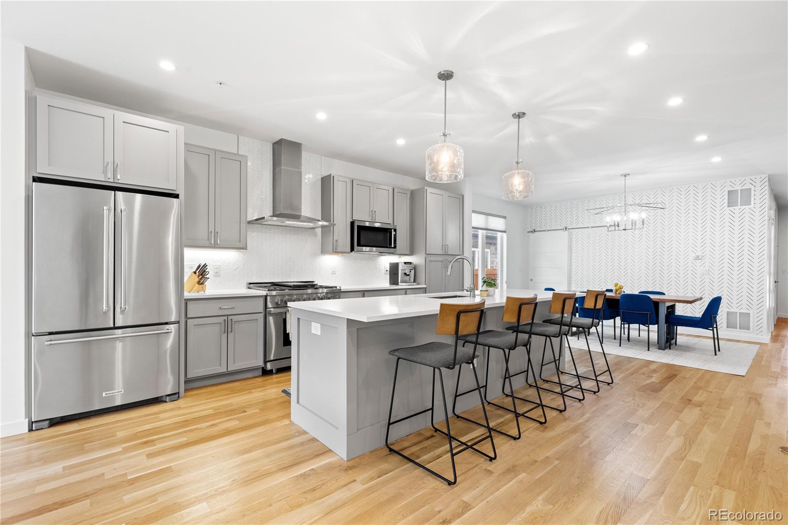 a kitchen with stainless steel appliances granite countertop a dining table chairs refrigerator sink and microwave