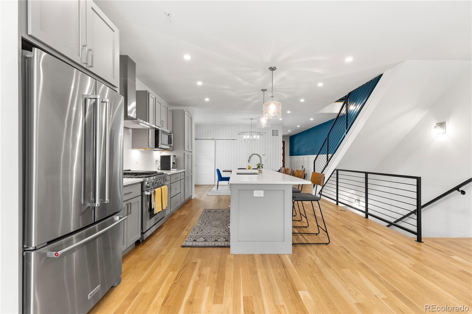 5327 Raleigh Street Denver, CO 80212 - Photo 10 of 40 a kitchen with stainless steel appliances a refrigerator a stove a kitchen island a dining table and chairs with wooden floor