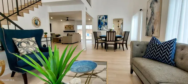 a living room with furniture potted plant and kitchen view