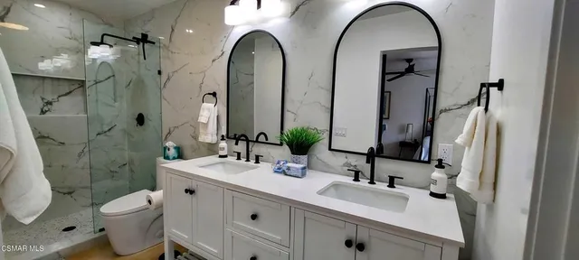 a bathroom with a double vanity sink toilet and shower