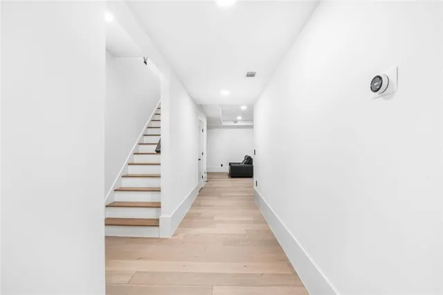 a view of a hallway with wooden floor and a bathroom