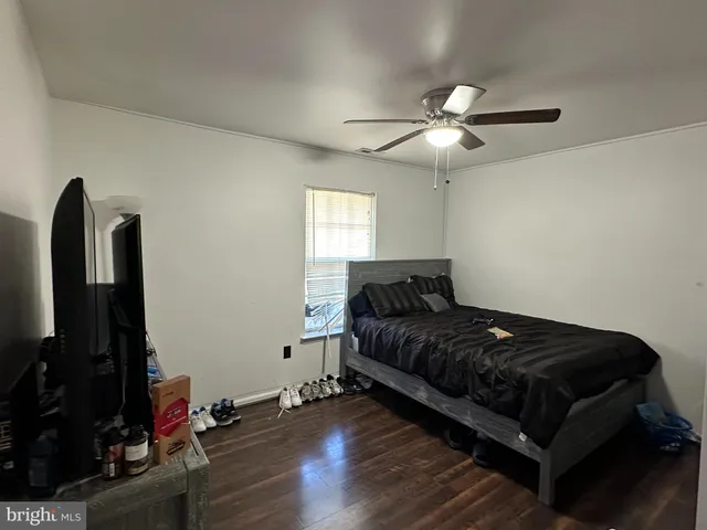 a living room with furniture a flat screen tv and a ceiling fan