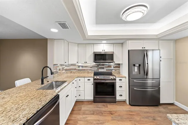 a kitchen with stainless steel appliances granite countertop a sink stove and refrigerator