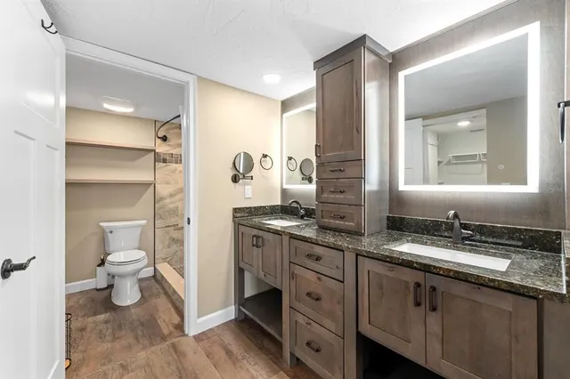 a bathroom with a granite countertop sink mirror and toilet