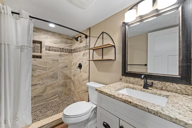 a bathroom with a granite countertop sink toilet and shower