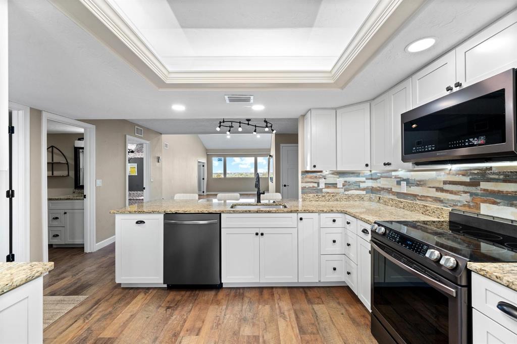 9604 Cortez Road West, Unit 136 Bradenton, FL 34210 - Photo 10 of 39 a kitchen with stainless steel appliances granite countertop a stove top oven a sink dishwasher and a microwave oven with wooden floor