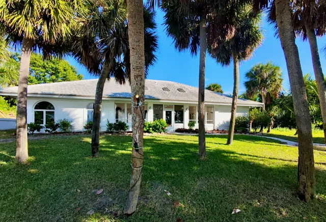 a view of a house with a yard park and palm trees
