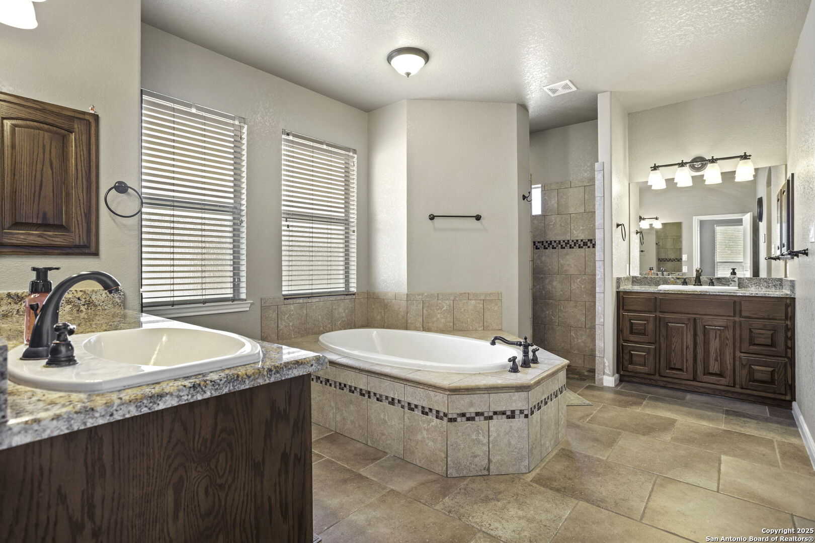 133 Copper Ridge Drive La Vernia, TX 78121 - Photo 22 of 35 a bathroom with a double vanity sink a mirror and a bathtub