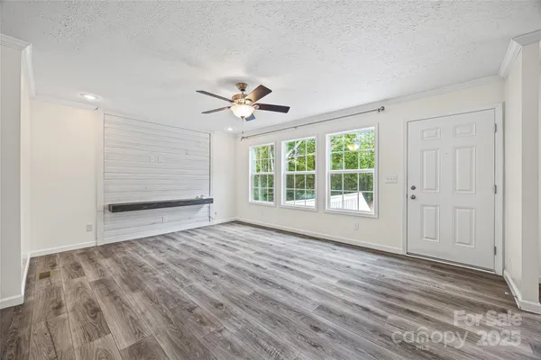 a view of an empty room with a window and wooden floor