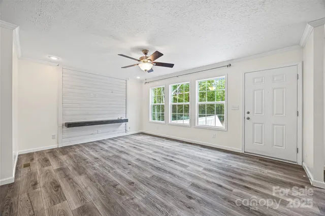 a view of an empty room with a window and wooden floor