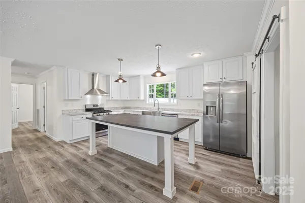 a kitchen with kitchen island granite countertop a sink cabinets and stainless steel appliances