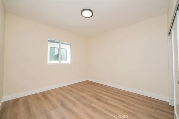an empty room with wooden floor and fan