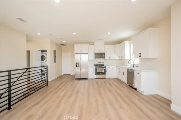 a kitchen with stainless steel appliances refrigerator cabinets and a wooden floor