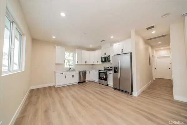 a large kitchen with stainless steel appliances kitchen island a large counter top and a refrigerator