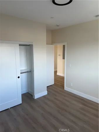 a view of an empty room with wooden floor and closet